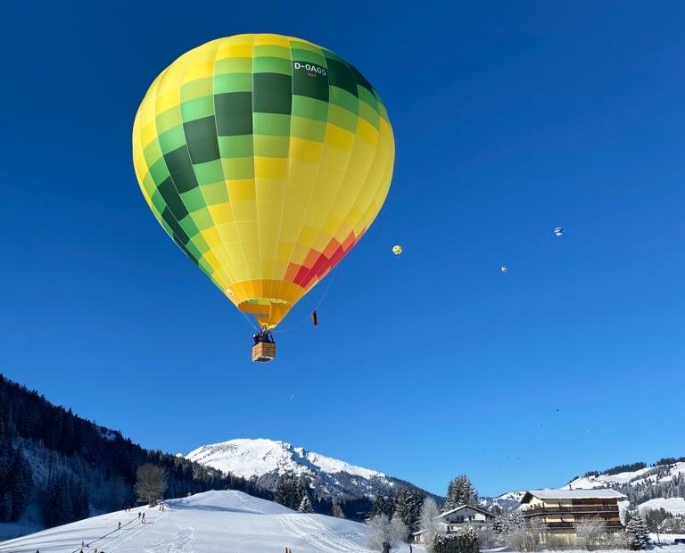 Gelber Ballon von CBT-Sports steigt in die Luft vor blauem Himmel in Tannheim